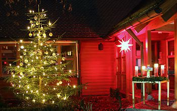 Geschmückter und beleuchteter Weihnachtsbaum und Stern vor dem Eingang der Versöhnungskirche