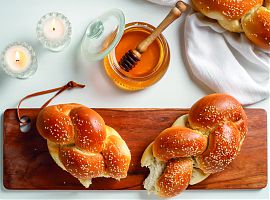 gedeckter Tisch mit Brot, Honig und Lichtern