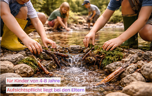 4 Kinder spielen in Gumistiefeln und kurzen Hosen an einem Bach.
