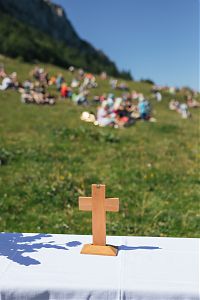 ein Kreuz im Vordergrund und im Hintergrund eine Bergwiese
