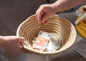 Ein geflochtenes Körbchen wird herumgereicht, um Geld einzusammeln. Ein paar Scheine und Münzen befinden sich bereits darin
